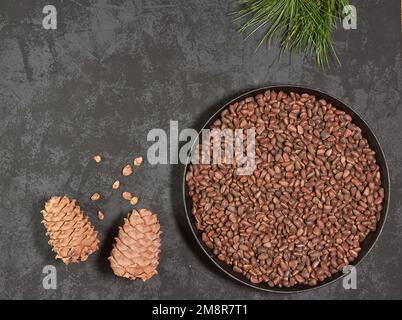 Pine cones and nuts in a frying pan on a dark background with space for copying, top view Stock Photo