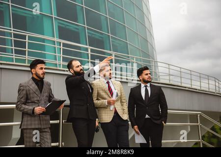 Business people outdoor meeting. Male employees in suits communicate outdoors. Business partners discuss and argue. Relationships and promotion Stock Photo