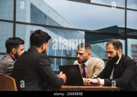 Corporate meeting of business partners outside the office. Male employees sit at the table and discuss the goals, ideas and plans of the company. Stock Photo
