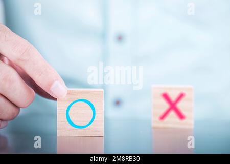 Businessman chooses a Yes or No symbols on wood blogs cube , Services and Customer satisfaction survey concept Stock Photo