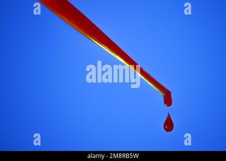 A drop of blood. Pipette. On a blue background. Dripping red liquid. A drop of red. Tests, blood group. Stock Photo