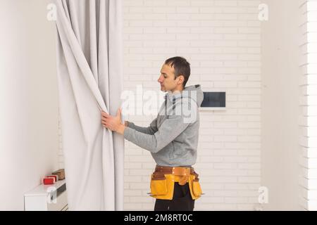 Young man installing curtains over window Stock Photo