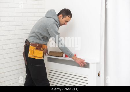 repairman using tools while installing or repairing heating radiator. plumber installing heating system in apartment. radiator installation, plumbing Stock Photo