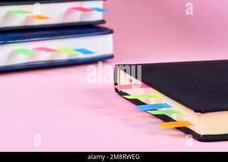 Close-up of an closed notepad with colorful sticky page markers on background of a stack of office notepads Stock Photo