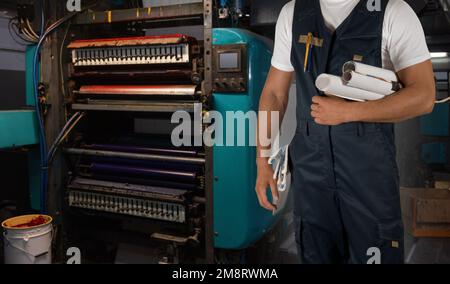 Man working in printing house with paper and printing machine Stock Photo
