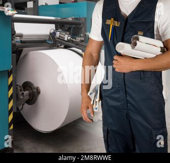 Man working in printing house with paper and printing machine Stock Photo