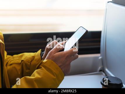 Male person using smartphone while traveling by train mobile phone in hands close up. Stock Photo