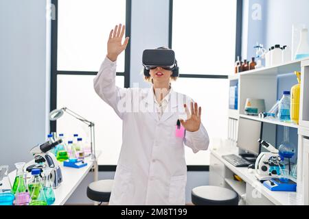 Young woman wearing scientist uniform using virtual reality goggles at laboratory Stock Photo