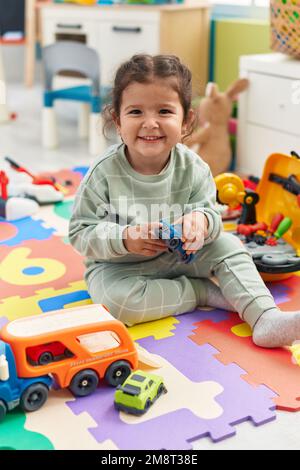 Adorable hispanic toddler playing with car toy sitting on floor at ...