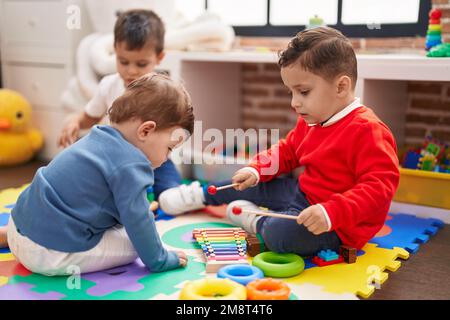 Group of kids playing xylophone sitting on floor at kindergarten Stock Photo