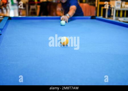 Player aiming cue in a billiard ball. Blurred person in the background Stock Photo