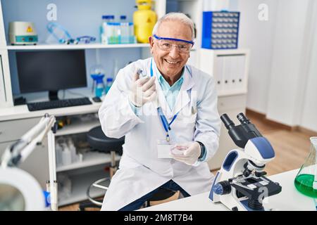 Senior man wearing scientist uniform using pipette working at laboratory Stock Photo