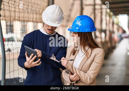 Mand and woman architects using touchpad write on report at street Stock Photo