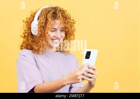 Smiley woman listening to music with a mobile and headphones Stock Photo
