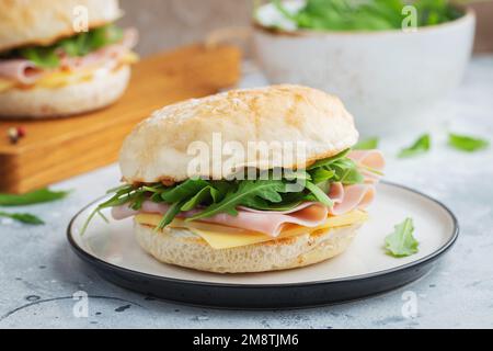 Two homemade sandwiches with ham, cheese and arugula on a concrete table. Stock Photo