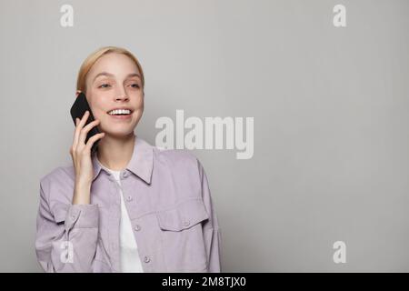 Young attractive blonde woman in casual clothes talking on phone against white studio wall banner background Stock Photo
