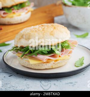 Two homemade sandwiches with ham, cheese and arugula on a concrete table. Stock Photo