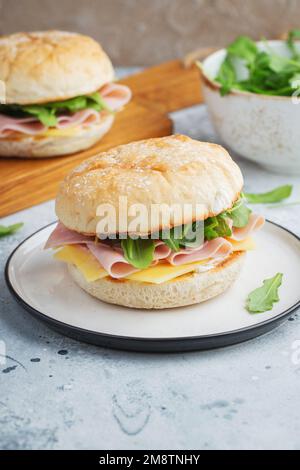 Two homemade sandwiches with ham, cheese and arugula on a concrete table. Stock Photo