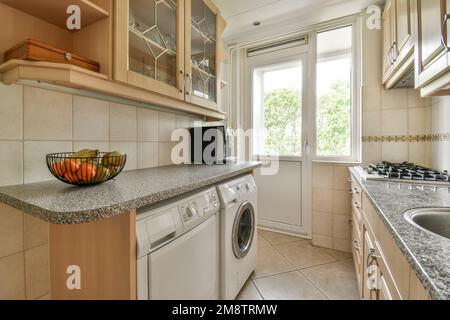 a kitchen area with a sink, stove and dishwasher on the counter in front of the washer