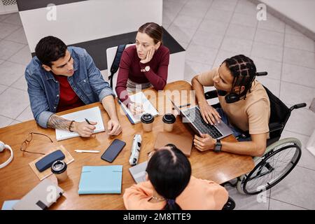 Top view at diverse group of young people studying together at table in college library, inclusivity concept Stock Photo