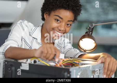 happy female pc-technician soldering a chip from a desktop computer Stock Photo