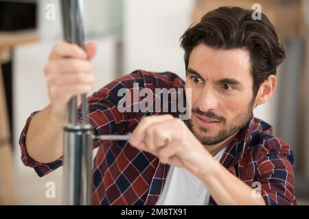 concentrated man in fixing a chair Stock Photo