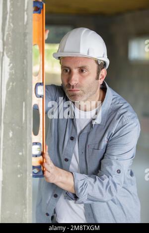mature worker using spirit level on a concrete wall Stock Photo