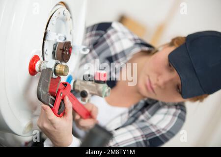 female technician servicing a boiler using tablet computer Stock Photo
