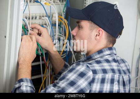 male engineer checking cables in a server Stock Photo