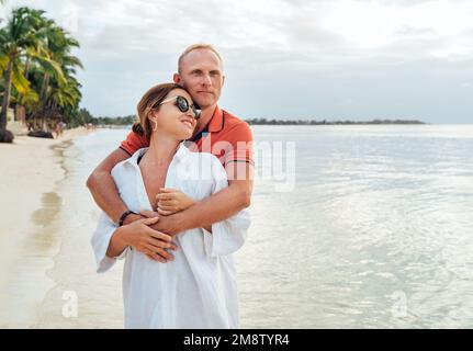 Couple in love hugging on the sandy exotic beach while they have a evening walk by the Trou-aux-Biches seashore on Mauritius island. People relationsh Stock Photo