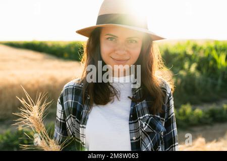 Portrait of a woman in a hat on the background of a sunset field Stock Photo