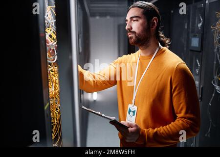 Side view portrait of bearded network technician working with server in data center Stock Photo