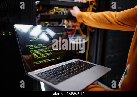 Closeup of IT engineer using laptop while setting up network in server room, copy space Stock Photo