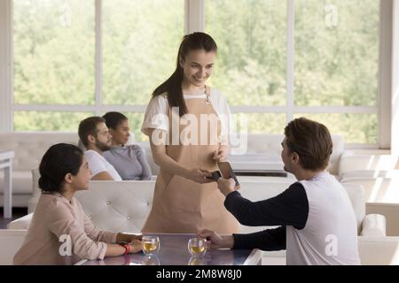 Cheerful young man and woman paying bill in cafe Stock Photo