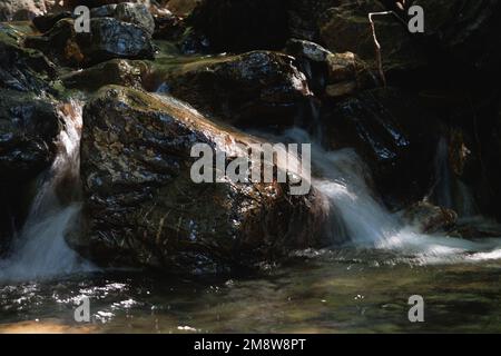 Close-up of Motion-Blurred Water Rapids Flowing over a Stone Stock Photo