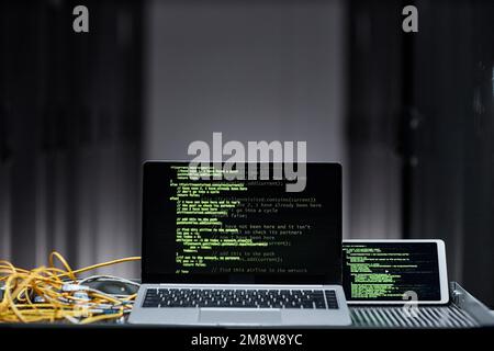 Minimal background image of laptop computer with green code lines on screen in server room, data security, copy space Stock Photo