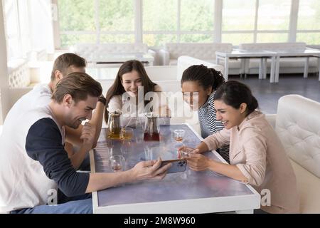 Diverse friends having fun in cafe, using mobile phone Stock Photo