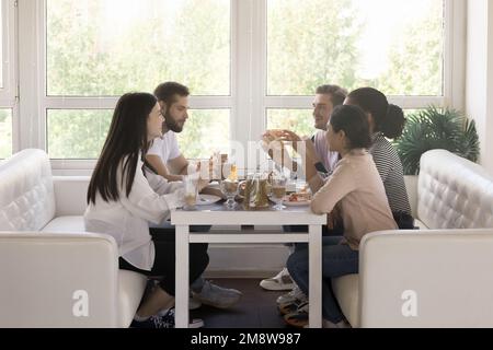 Group of young friends meeting for dinner in cafe together Stock Photo
