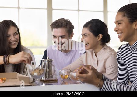 Diverse group of young friends gathering at table in cafe Stock Photo