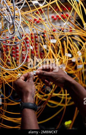 Vertical close up of male hands connecting cables and wires in server room while setting up network, copy space Stock Photo