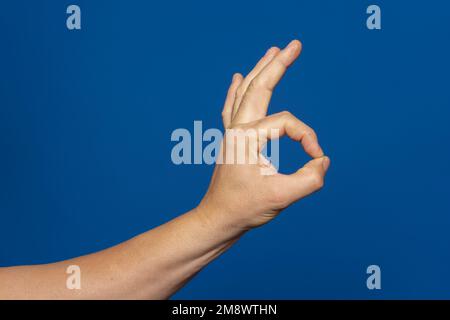 Strong hand of man making the ok gesture isolated on blue background. Everything ok, good job. Stock Photo