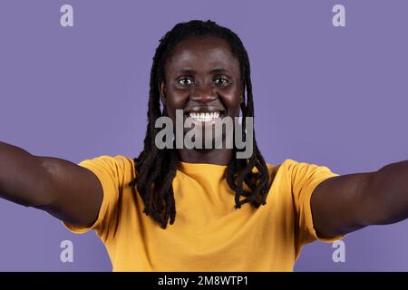 Closeup of happy handsome black guy taking selfie on blue Stock Photo