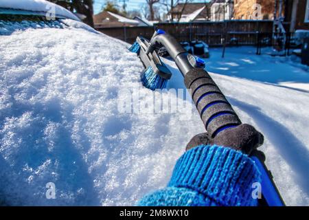 Cleaning snow off windshield perspective picture from point of view of person cleaning with long handled brush - selective focus - room for copy Stock Photo