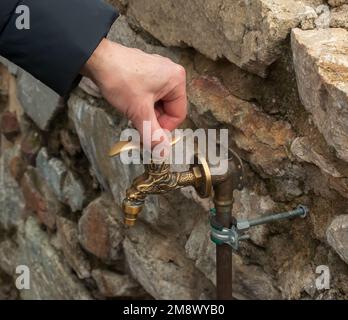 Antique brass water faucet as an architectural monument. Old tap with water on the street. Stock Photo