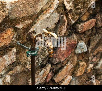 Antique brass water faucet as an architectural monument. Old tap with water on the street. Stock Photo