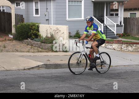 Smiling Caucasian senior man cycles up a steep hill, exemplifying commitment to an active lifestyle. Stock Photo