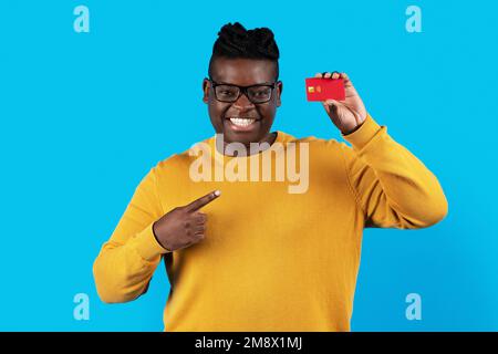 Cheerful Black Man Pointing At Credit Card In His Hand Stock Photo