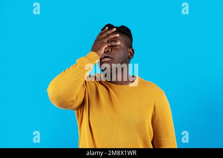 Young Black Man Doing Facepalm Gesture While Standing Isolated Over Blue Background Stock Photo