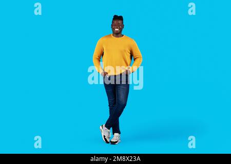 Handsome black man standing with hands in pockets over blue background Stock Photo