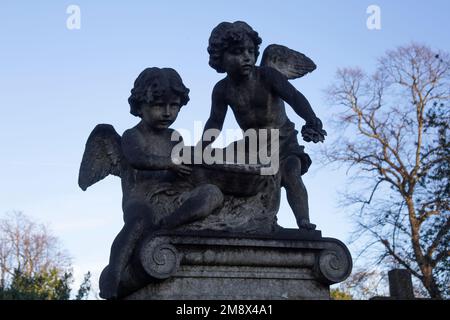 The two ‘putti’ - winged children - scattering flowers on the grave of Albert Emile Schloss Brompton Cemetery, West London UK Stock Photo